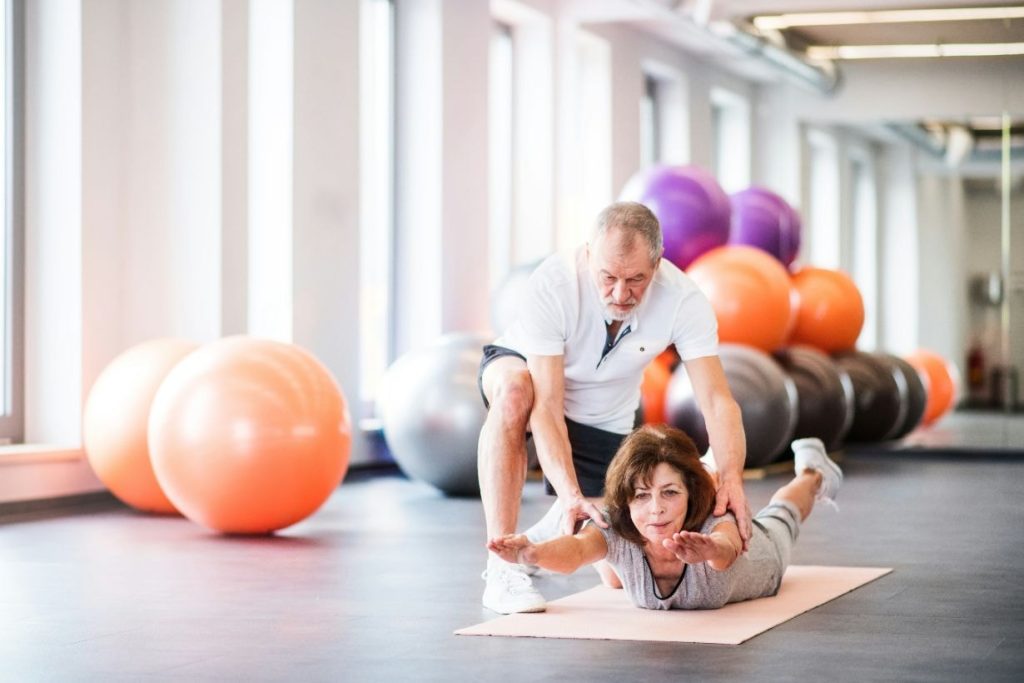 Senior physiotherapist working with old female patient