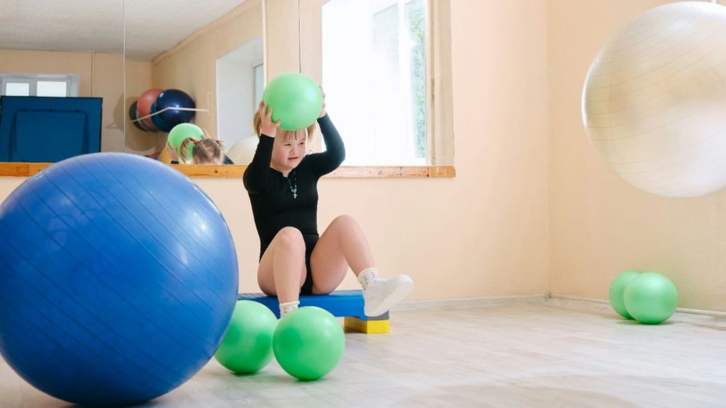 Child with Down syndrome playing with the exercise ball