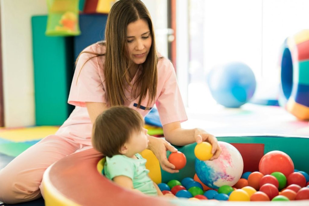 Child playing with balls while being attended by a paediatric physiotherapist