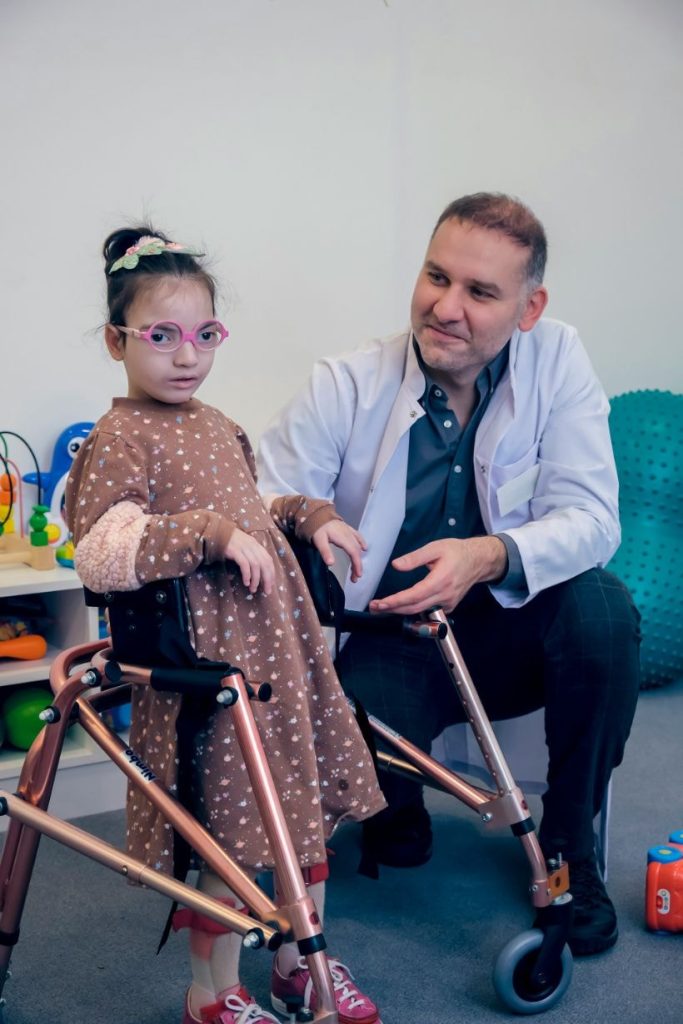 Physiotherapist helping the child to walk