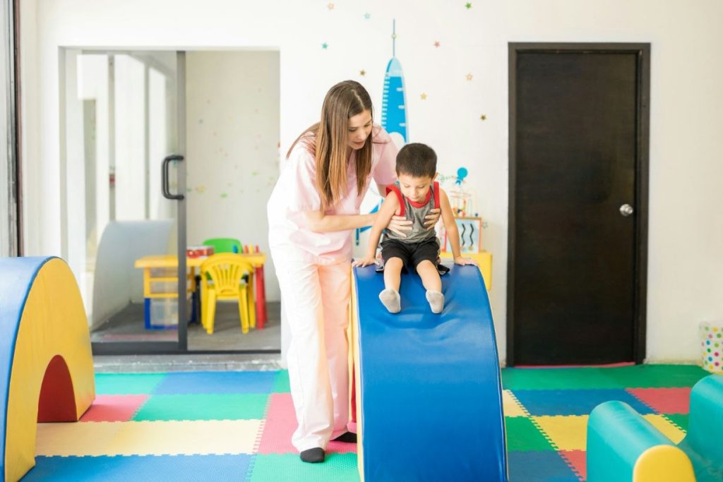 Little boy doing physical exercise using an obstacle course with a therapist