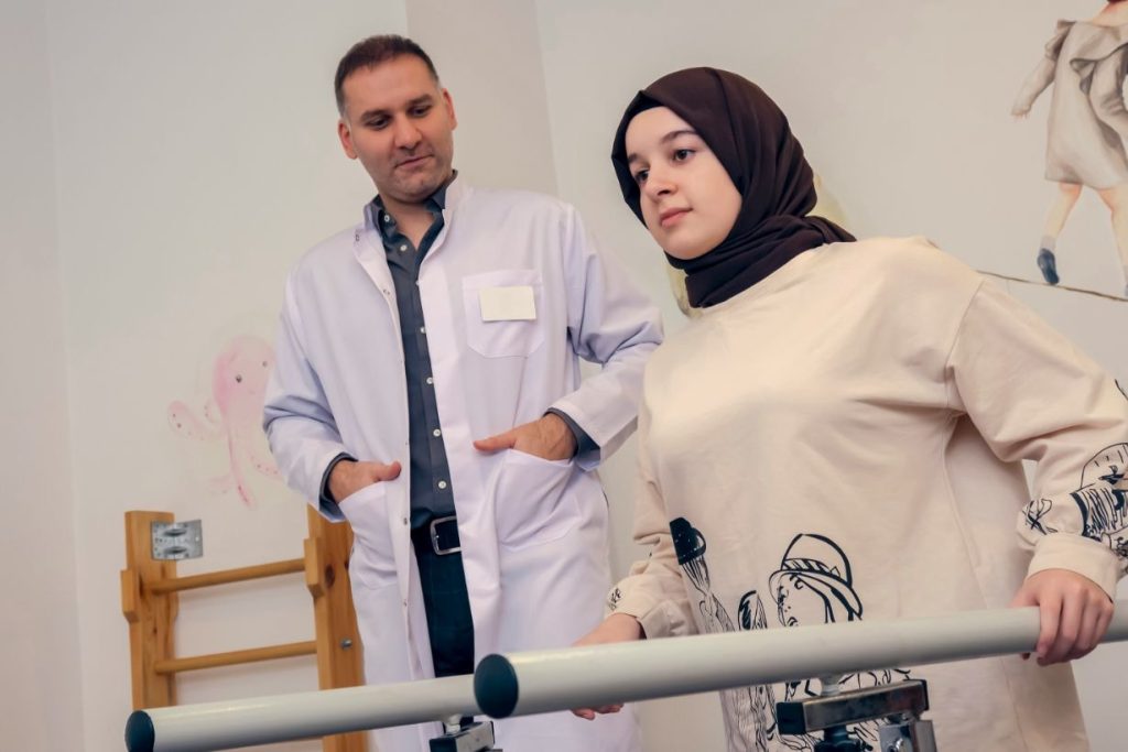 Physiotherapist with lady trying to walk using hand rails